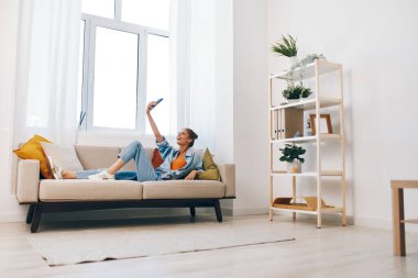 Mutlu Kadın Cep Telefonu Tutuyor ve Gülümsüyor, Koltukta Rahatlıyor