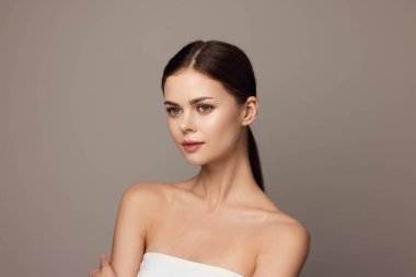 Beyaz elbiseli güzel bir kadın kollarını kavuşturup kameraya bakıyor..