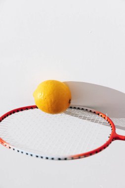 Limon ve badminton raketi beyaz yüzeye gölge düşürüyor.