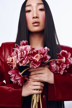 Uzun siyah saçlı, kırmızı ceketli, elinde bir buket çiçekle güzel bir kadın.