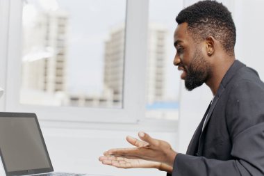 Çağdaş bir ofis ortamında dizüstü bilgisayar ve not defteriyle masa başında çalışan konsantre bir adam..