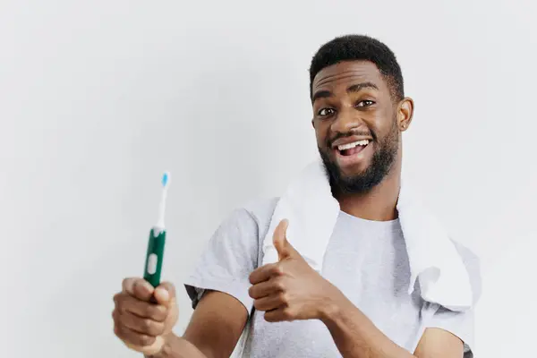 stock image Man holding a toothbrush and giving a thumbs up, promoting dental hygiene and oral care on a clean white background.