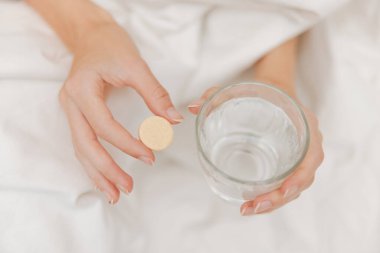 Hasta bir adam elinde bir hap ve bir bardak su tutarak yatakta yatıyor. sağlık hizmeti kavramı.