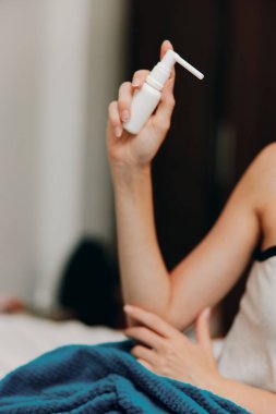 Yanında bir şişe dezenfektanla yatakta oturan bir kadın..