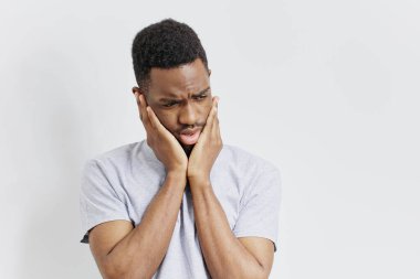 Şok olmuş bir adam, saf beyaz bir arka plana karşı yüzünü inançsızlıkla tutuyor..