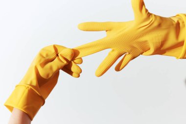 Sarı lastik eldiven giyen iki kişi yakın çekimde birbirlerine uzanıyorlar..