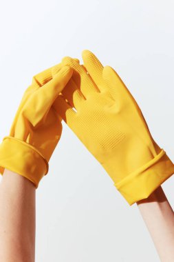 Sarı lastik eldivenler beyaz arka planda elle tutuluyor..