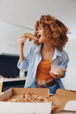 Pizza kutusunun önünde pizza yemekten hoşlanan bir kadın modern bir hayat tarzında.