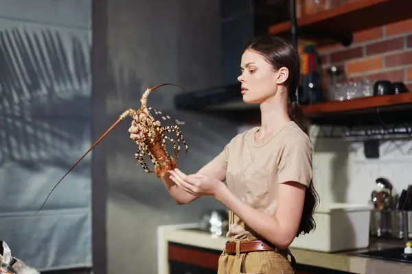 stock image Woman holding a lobster in front of a kitchen counter, preparing a delicious seafood meal for dinner