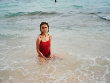 Atletik vücutlu kırmızı mayo giymiş seksi bir kadın okyanusta suyun içinde duruyor ve ufka bakıyor. Yüksek kalite fotoğraf