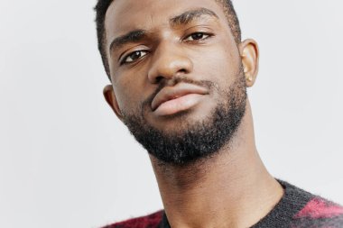 Kırmızı ve siyah kazaklı kendine güvenen bir adam içeride dikiliyor, düşünceli bir şekilde ileriye bakıyor, içgözlem duygusunu aktarıyor..