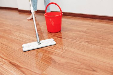 Ahşap zemini kova ve paspasla temizleyen kadın. Ev işleri konsepti. Parlak ve temiz oturma odası. profesyonel temizlik servisi.