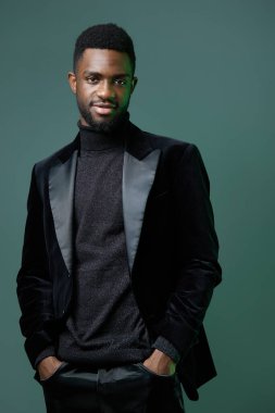 Siyah balıkçı yaka ve takım elbiseli zarif Afro-Amerikan erkeği tarafsız bir geçmişe karşı özgüvenle duruyor..