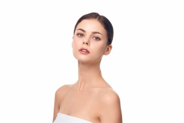 Kafasında beyaz havlu olan kadın, gözleri kapalı ve gülümsüyor, yana bakıyor..