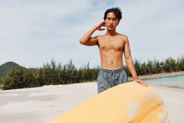 Kayak Macerası: Mutlu bir Asyalı adam Tropik bir plajda yaz tatilinin tadını çıkarıyor, Gök Denizi 'nde kürek çekiyor