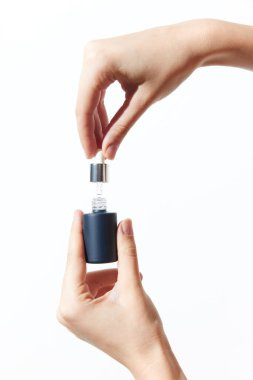 İki el, üzerinde kapağı olan küçük bir şişeyi tutuyor. Bir insanın küçük bir kabı kapakla kavradığı basit ve minimalist bir görüntü, sağlık, hijyen ya da güzellik gibi kavramları çağrıştırıyor.