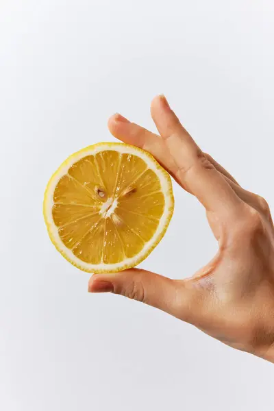 stock image Hand holding half of a lemon on a white background with empty space in the middle.