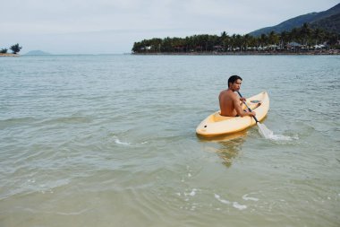 Mutlu Asyalı Adam Tropik Plaj Cenneti 'nde kayak yapıyor.