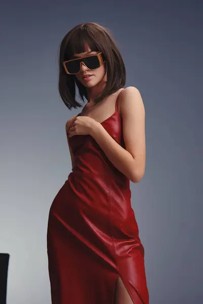 stock image Woman, red dress, sunglasses, photo backdrop a woman in a red dress and sunglasses poses confidently in front of a stylish black and white backdrop, blending fashion and elegance in a striking d