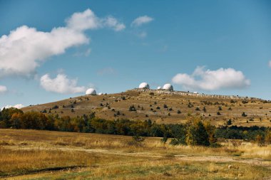 Tepenin tepesindeki üç teleskop çarpıcı bir mavi gökyüzü keşfi ve doğadaki maceraya bakıyor.