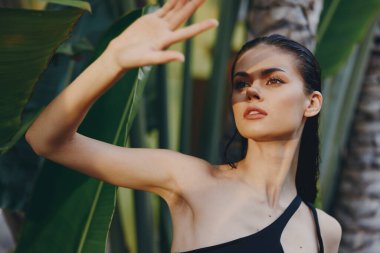 Siyah elbiseli kadın Palm Tree 'nin önünde duruyor. El havada, yaz güneşinin altında.