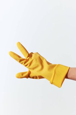 Sarı lastik eldivenli kişi beyaz arka planda barış işareti yapıyor..