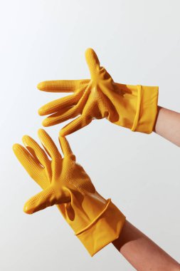 Sarı lastik eldivenler beyaz arka planda elle tutuluyor. Temizlik ve ev işleri için bir çift eldiven. Temizlik malzemeleri konsepti için parlak ve renkli görüntü.