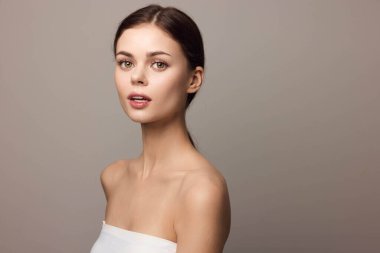 Gri arka planda beyaz elbiseli güzel bir kadının portresi..