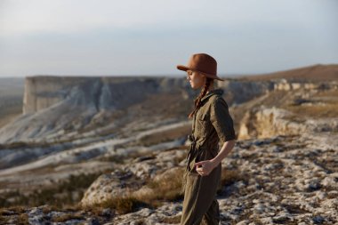 Tepenin tepesinde şapkalı bir kadın, dağ arkası yolculuk macerası, güzellik, doğaya bir yolculuk.