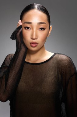Asyalı kadın gri arka plan pozu veriyor. Şık ve şık görünüm..