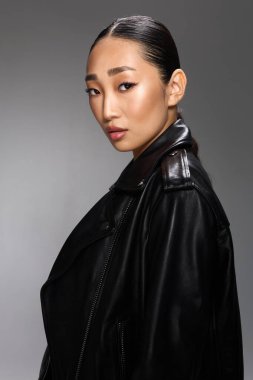Asyalı kadın siyah deri ceket kamera grisi arka plan.