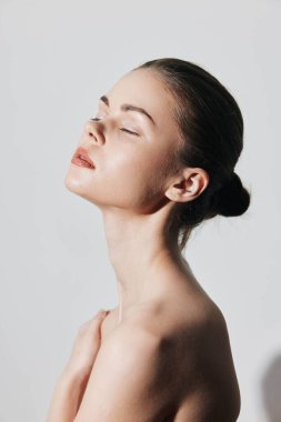 Sakin ve zarif genç bir kadın. Gözleri kapalı. Temiz beyaz arka planda huzurlu bir portrede.