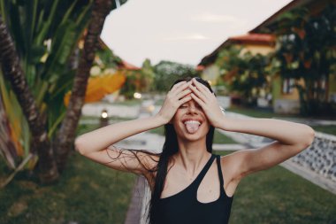 Palmiye ağacının önünde duran kadının gözleri, düşünceli bir iç gözlem ve yansıma anı ile kaplıydı.