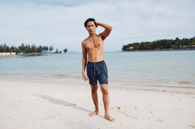Gülümseyen Asyalı Adam Tropikal Plaj Tatilinde: Kaslı Gövde ve Mutlu Yaz Titreşimleri