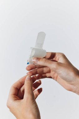 Parmaklarında küçük plastik parçaları tutan iki beyaz bandajlı birey..