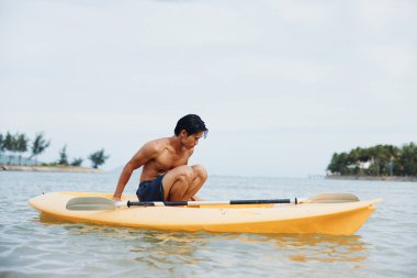 Serene Summer: Mutlu Asyalı Adam Tropik Sahilde Kayak Yapıyor