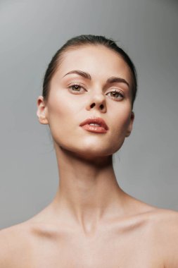 Gri arka plan, güzellik ve cilt konsepti üzerine bir stüdyo resminde temiz tenli güzel bir genç kadın.