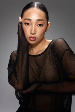 Asyalı kadın fotoğraf grisi arkaplan pozu verdi.