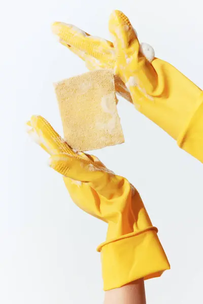 stock image Person wearing yellow rubber gloves holding soap and sponge for cleaning.