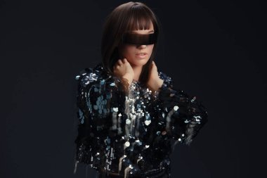 Sequin ceket, güneş gözlüğü, kadın, siyah arkaplan pullu ceket ve güneş gözlüklü bir kadın kameraya dramatik bir şekilde poz veriyor, elleri yüzünde, parlak siyah bir fonda.