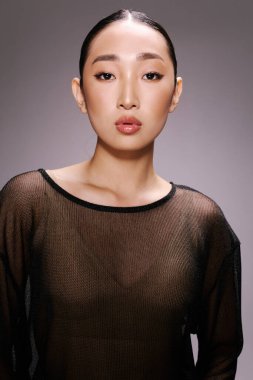 Asyalı bir kadın, üstü açık, kameraya poz veriyor, elleri kalçasında. Şık ve şık bir görünüş. Reklam ve moda kavramları için uygun.