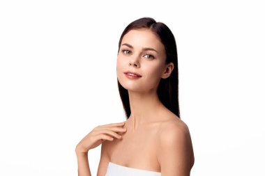 Beyaz havluyla poz veren bir kadın elini omzuna koyup beyaz arka planda izole bir şekilde kameraya bakıyor..