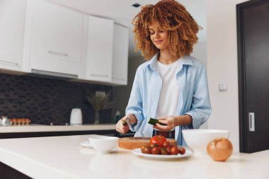Afro-Amerikalı kadın mutfağında lezzetli yemekler pişiriyor. Hazırlık ve malzemelere odaklanıyor.