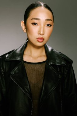 Asyalı kadın, moda, siyah deri ceket, eller kalçada, kamera önünde poz veriyor..