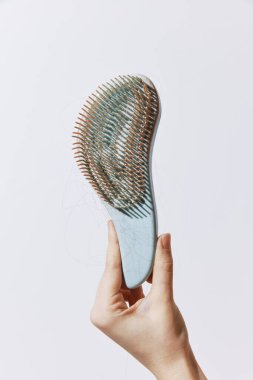 Beyaz arkaplanda kişi tarafından tutulan taraklı fırça.