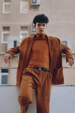 Kahverengi balıkçı yaka ve takım elbise giyen, modern entelektüellik saçan modaya uygun bir erkek model.