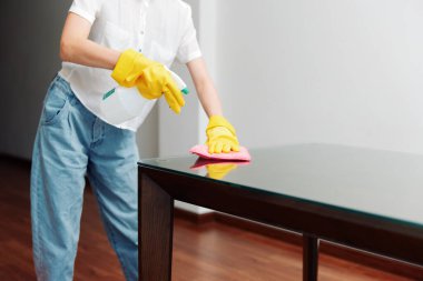 Woman cleaning glass table with mop and bucket of water in background. clipart