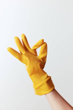 Sarı lastik eldiven giyen biri, bir elinde başka bir eldiven tutarken, bir elinde 