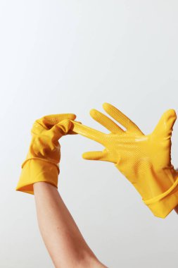 Sarı lastik eldiven giyen biri bir eliyle dokunmak için uzanırken diğer eliyle başka bir eldiven tutuyor..