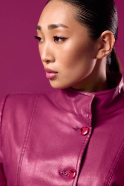 Mor deri ceketli, at kuyruklu, gözleri kapalı, kameraya bakmayan Asyalı esmer kadın..